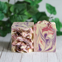 Load image into Gallery viewer, Two marbled soap bars on a wooden surface with green leaves in the background