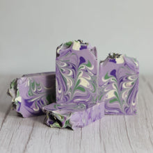 Load image into Gallery viewer, Three pieces of marbled purple soap on a light wooden surface.
