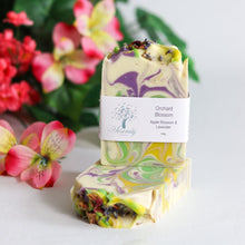 Load image into Gallery viewer, Colorful soap bar with a label in front of flowers