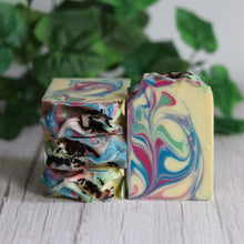 Load image into Gallery viewer, Colorful marbled soap bars on a wooden surface with green leaves in the background