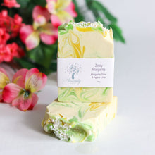 Load image into Gallery viewer, Marbled soap bar with a label in front of pink flowers