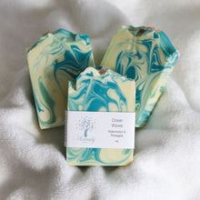 Load image into Gallery viewer, Three marbled soap bars with a label on a white fabric background
